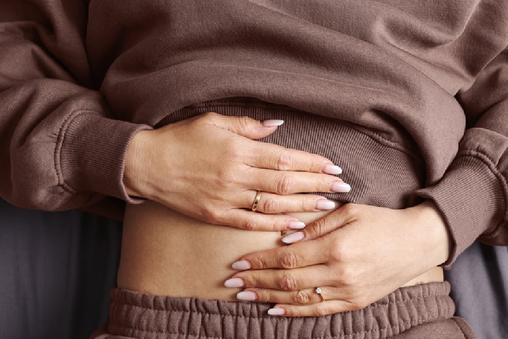 Person resting their hands on their abdomen to represent stomach noises and digestive health.